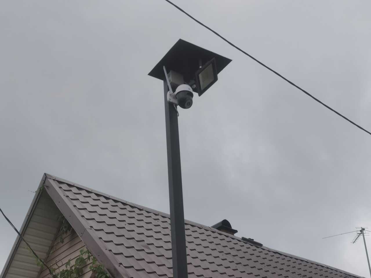 Камера и освещение на столбе с крышей для защиты от дождя и снега